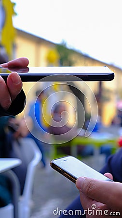 woman& x27;s hand with phone checks qrcode, green pass, on man& x27;s phone, in open environment Stock Photo