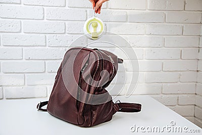 A woman& x27;s hand puts a collapsible silicone green glass for hot drinks in a backpack. Zero waste concept Stock Photo
