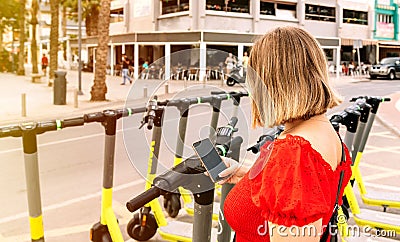 Woman's hand scans with a mobile phone the QR code of a scooter Stock Photo