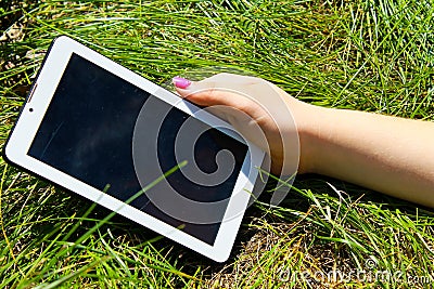 Woman's hands holding tablet laying on grass Stock Photo