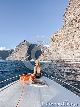 Woman on the yacht nose near the rocky coast Stock Photo