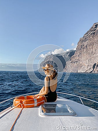 Woman on the yacht nose near the rocky coast Stock Photo