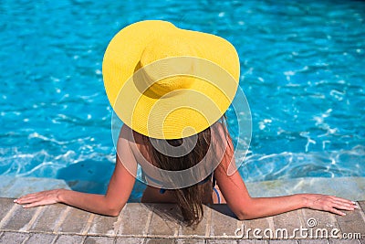 Woman in yellow hat relaxing at swimming pool Stock Photo