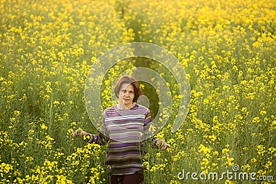 Woman on a yellow rapeseed field in the evening at sunset Stock Photo