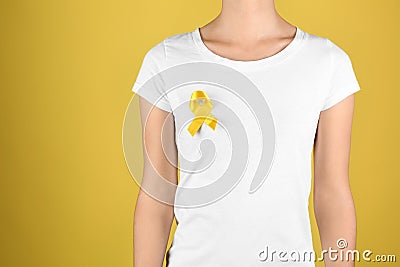 Woman with yellow ribbon on color background. Cancer awareness concept Stock Photo