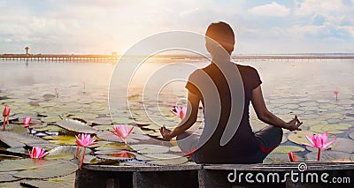 Woman yoga practicing and meditating by the red lotus lake background Stock Photo