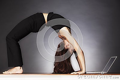 Woman in yoga wheel pose with laptop. Stock Photo