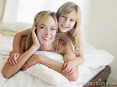 Woman and young girl lying in bed smiling Stock Photo