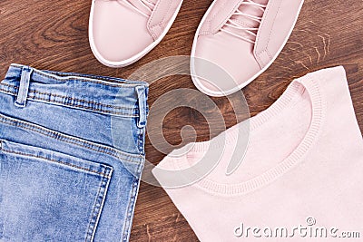 Womanly pink leather shoes, jeans pants and sweater on rustic boards Stock Photo