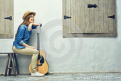 Womann sitting on bench with guitar. Stock Photo