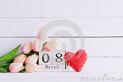 Womans day concept. Pink tulips and red heart with March 8 text on wooden block calendar on white wooden background Stock Photo