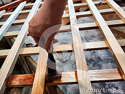 A womans hand with a bad old brush paints a wooden lattice trellis. Construction and decorative work Stock Photo