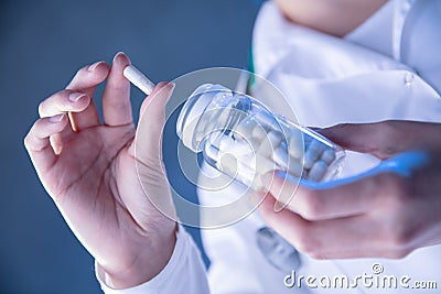 Womans hand holds white pill pulled out from jar Stock Photo