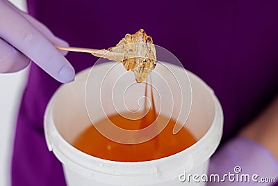 Women beautician holds jar wax of paste for sugar depilation shugaring, white background Stock Photo