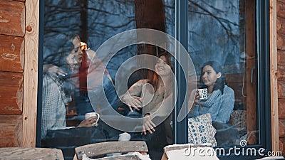 Women, best friends having fun winter holidays in wooden mountain house. Drinking hot beverages and gossiping near the Stock Photo