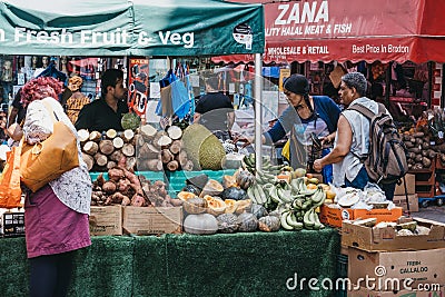 Women buy fresh fruits and vegetables from Brixton Market, London, UK Editorial Stock Photo