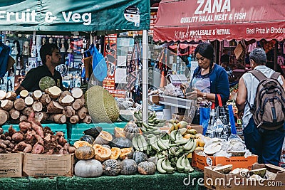 Women buy fresh fruits and vegetables from Brixton Market, London, UK Editorial Stock Photo