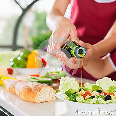 Women cooking fresh salad and pour olive oil. Healthy food Stock Photo