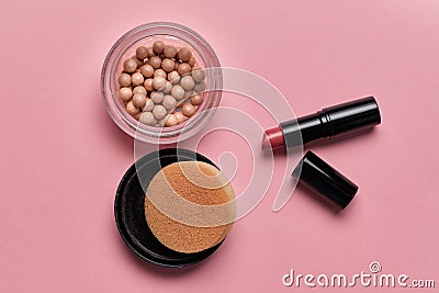 Women cosmetic powder in balls and lipstick on a pink background Stock Photo