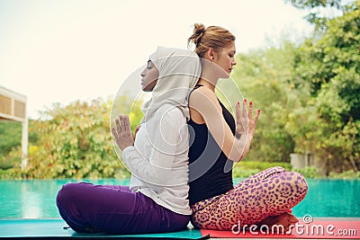 Women doing yoga by the poolside Stock Photo