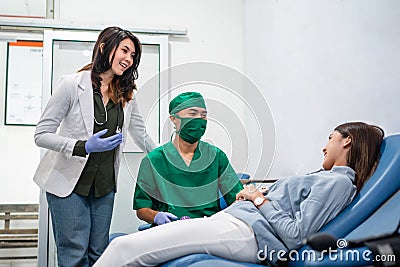 a woman donor lies down during a blood transfusion with two doctors Stock Photo