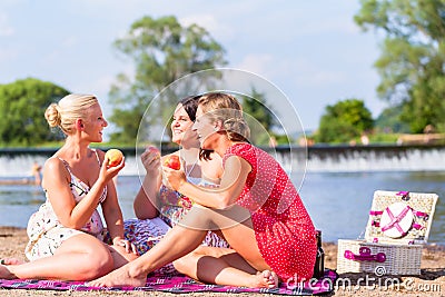 Women eating fruit at river beach picnic Stock Photo