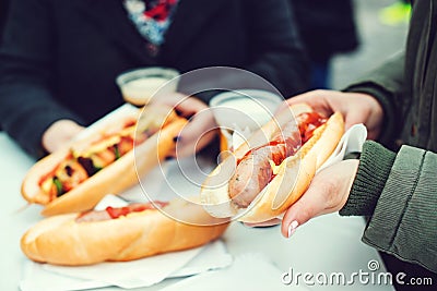 Women eating sausage at street food festival. Czech market in Prague. Street food at winter time in European town. Travelling and Stock Photo