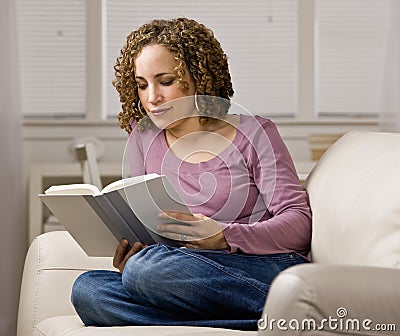 Women enjoying reading a book in livingroom Stock Photo