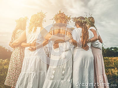 Women in flower wreath on sunny meadow, Floral crown, symbol of summer solstice. Stock Photo