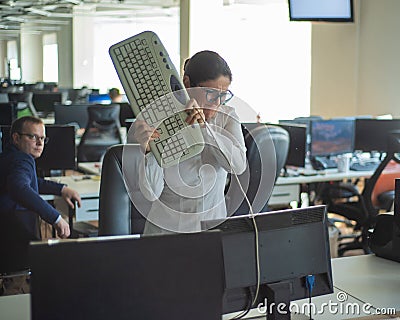 A woman freaks out and gets depressed from a mistake and breaks the keyboard on the monitor. Female manager gets angry Stock Photo