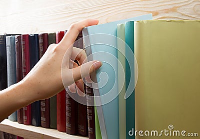 Women Hand selecting book from a bookshelf in library. Back to school. Stock Photo
