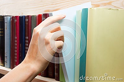 Women Hand selecting book from a bookshelf in Stock Photo