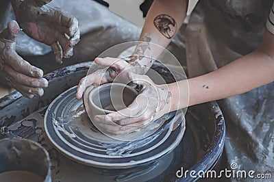 Women hands. Potter at work. Creating dishes. Potter`s wheel. Dirty hands in the clay and the potter`s wheel with the Stock Photo