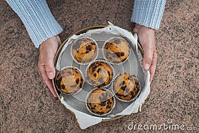 Women holding a lot of muffins with chocolate - marron background Stock Photo