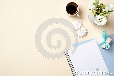 Women home office desk with blank paper notepad, coffee cup, gift box, flowers bouquet and feminine fashion accessories on beige Stock Photo