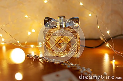 Women parfume Avon in glass clear bottle near golden bride accessories for hair and blurred lights Editorial Stock Photo