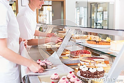 Women in pastry shop filling up sales display with pies Stock Photo