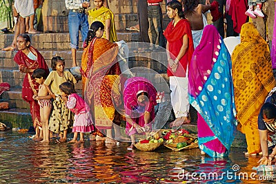 Women pilgrims pray at the bank of the Holy Ganges river at sunrise in Varanasi, India. Editorial Stock Photo