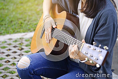 Women playing acoustic guitar in the garden Stock Photo