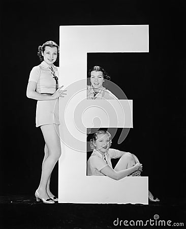 Women posing with huge letter E Stock Photo