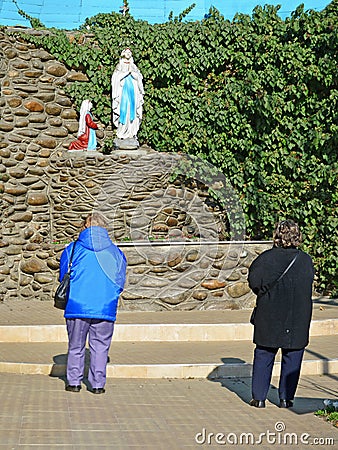 Women prayers in front of a Lourdes grotto, catholic shrine. Editorial Stock Photo