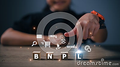 Women press their fingers on the wooden cubes with BNPL with online shopping icons. BNPL Buy now pays later online shopping Stock Photo