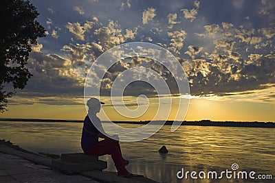 Women at river bank watching sunset Stock Photo