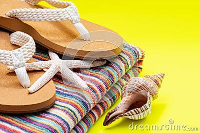 Women`s Causal natural color Beach Flip Flops and Colorful Striped Beach Towel decorated with White Finger Starfish and Seashells Stock Photo