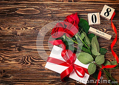 Women`s day background. 8 march wooden calendar, red roses, gift with red ribbon on the wooden background. Copy space, flat lay Stock Photo