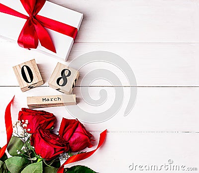 Women`s day background. 8 march wooden calendar, red roses, gift with red ribbon on the white wooden background. Copy space, flat Stock Photo