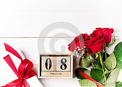 Women`s day background. 8 march wooden calendar, red roses, gift with red ribbon on the wight wooden background. Copy space, flat Stock Photo