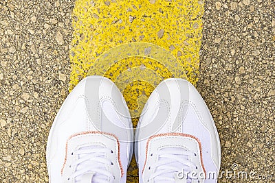 Women`s feet on the road. White sneakers on asphalt top view Stock Photo