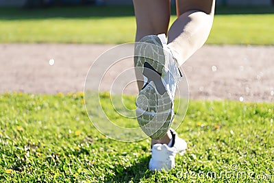 Women`s feet in sneakers. Grass running. On the grass Stock Photo