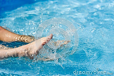 Women`s feet splashing in the pool, water spray Stock Photo